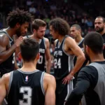 Austin Spurs players huddle during a timeout, with Hedo Turkoglu observing from the sideline