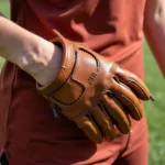 Woman's hand wearing a brown leather softball glove