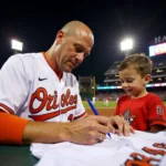 Cal Ripken Jr. signing a baseball jersey for a fan.